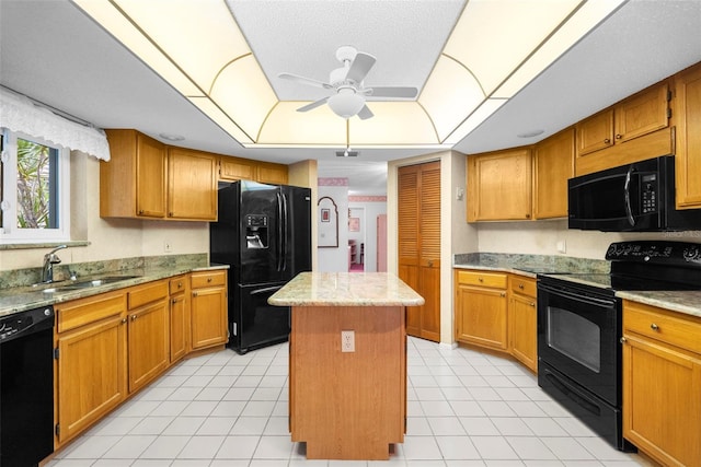 kitchen featuring light stone counters, black appliances, ceiling fan, a center island, and sink