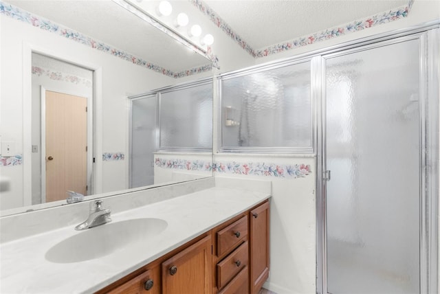 bathroom featuring walk in shower, vanity, and a textured ceiling