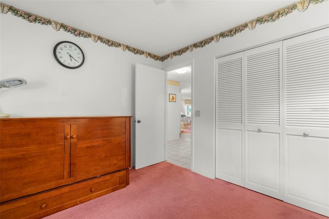 unfurnished bedroom with light carpet, a textured ceiling, and a closet