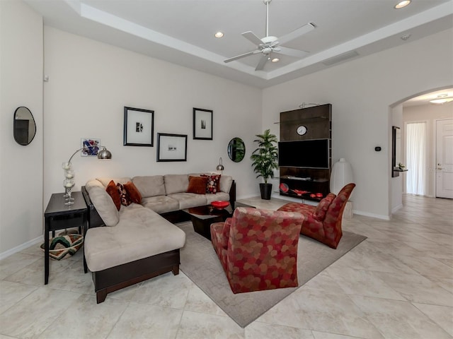 living room with ceiling fan, light tile patterned flooring, and a tray ceiling