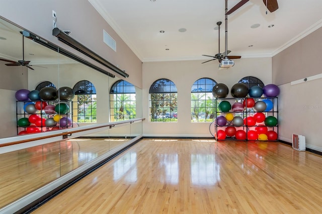 workout room featuring ornamental molding, light wood-type flooring, and ceiling fan