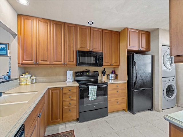 kitchen featuring light tile patterned flooring, stacked washer / dryer, sink, and black appliances