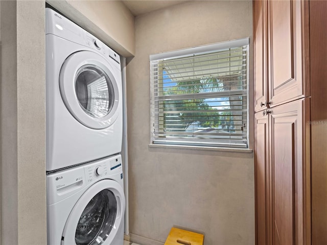 laundry room with cabinets and stacked washer and clothes dryer