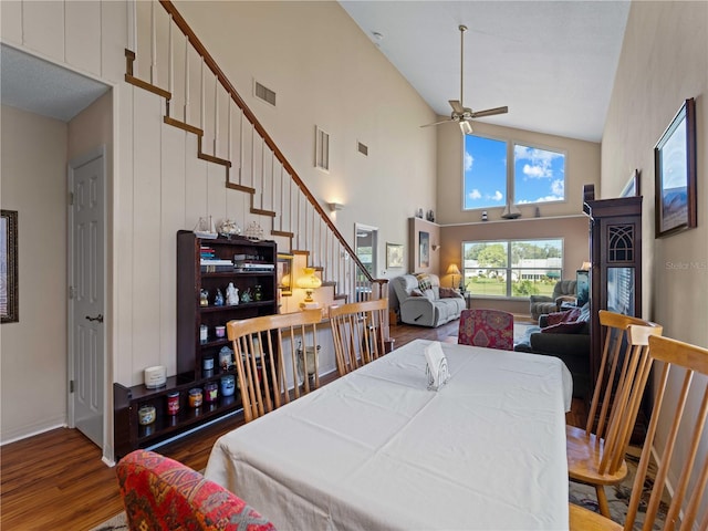 dining area with wood-type flooring, ceiling fan, and high vaulted ceiling