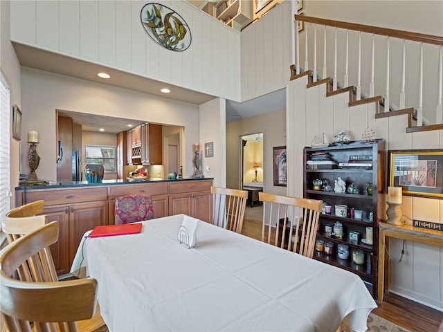 dining space with a towering ceiling and dark wood-type flooring