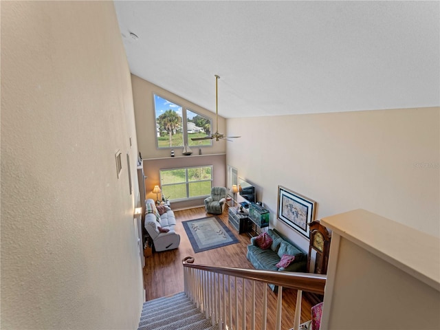 stairway featuring hardwood / wood-style floors, ceiling fan, and high vaulted ceiling