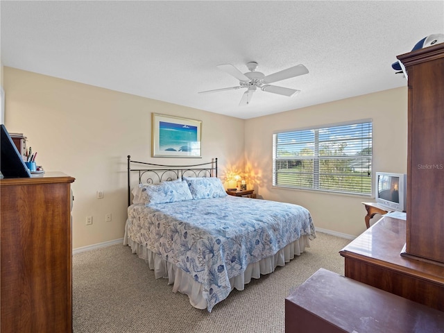 carpeted bedroom with ceiling fan and a textured ceiling