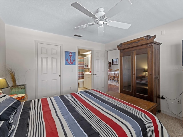 bedroom featuring ceiling fan, ensuite bathroom, and a textured ceiling