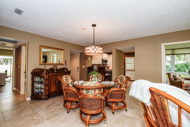 dining area featuring light tile patterned floors and a textured ceiling