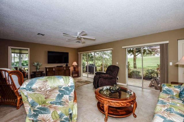 living room featuring plenty of natural light, ceiling fan, and a textured ceiling