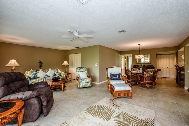 tiled living room with a textured ceiling and ceiling fan with notable chandelier