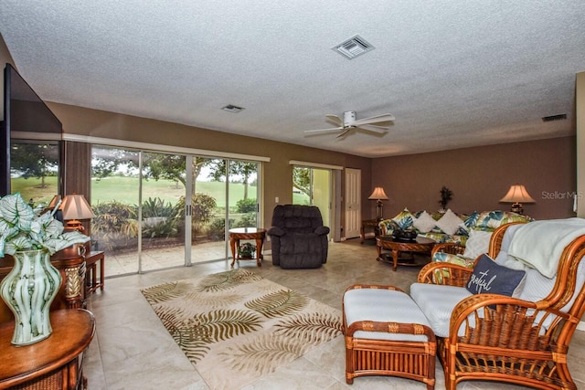 living room featuring ceiling fan, light tile patterned floors, and a textured ceiling