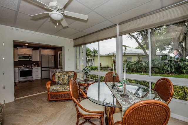 sunroom with a paneled ceiling and ceiling fan