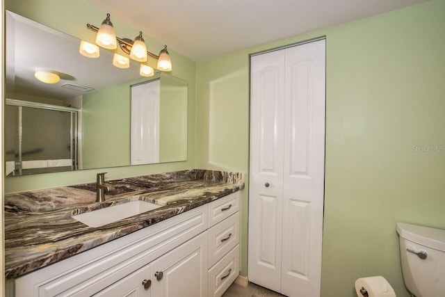 bathroom featuring vanity, toilet, and a shower with door