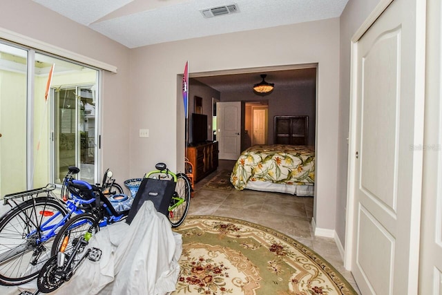 bedroom featuring light tile patterned floors, a textured ceiling, and a closet