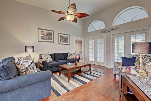 living room with wood-type flooring, ceiling fan, french doors, and high vaulted ceiling