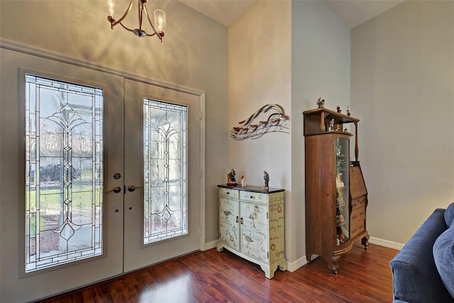 foyer with lofted ceiling, dark wood-type flooring, french doors, and a notable chandelier