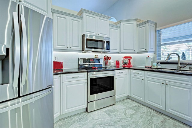 kitchen with white cabinets, vaulted ceiling, appliances with stainless steel finishes, and sink