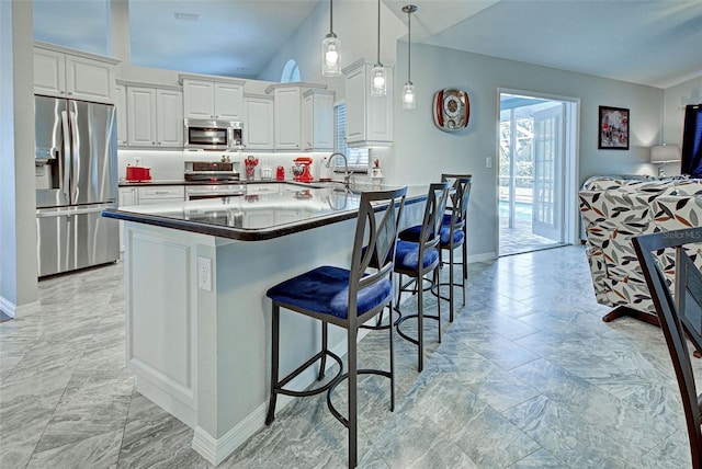 kitchen featuring white cabinets, kitchen peninsula, decorative light fixtures, stainless steel appliances, and a kitchen breakfast bar