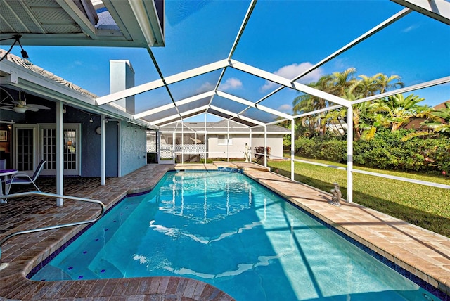 view of swimming pool featuring a patio, ceiling fan, and glass enclosure