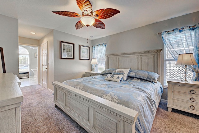 carpeted bedroom featuring ceiling fan, ensuite bathroom, and multiple windows