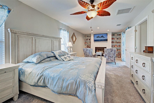 bedroom with ceiling fan, a tiled fireplace, and light carpet