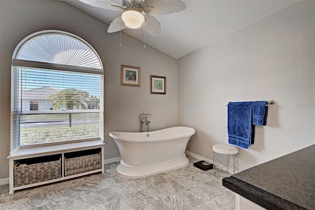 bathroom featuring ceiling fan, plenty of natural light, vaulted ceiling, and a washtub