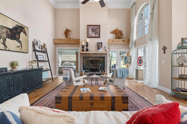 living room with ornamental molding, a towering ceiling, ceiling fan, and hardwood / wood-style flooring