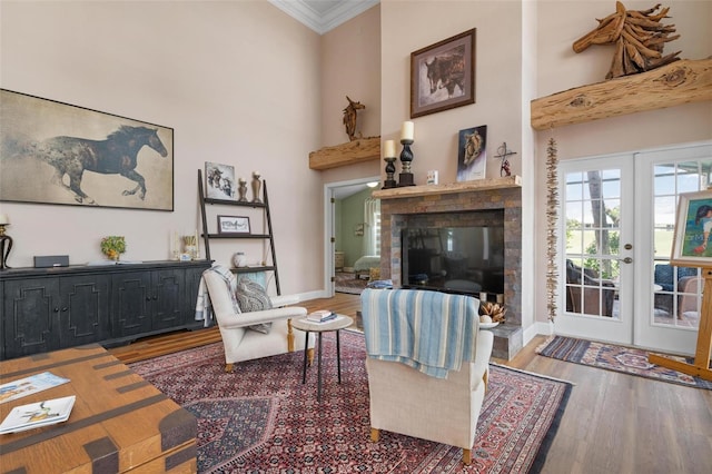 living room featuring french doors, hardwood / wood-style flooring, a towering ceiling, and ornamental molding