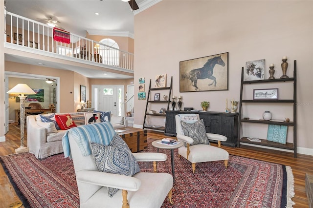 living room with wood-type flooring, ceiling fan, and a high ceiling