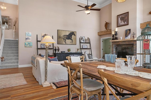 dining room featuring ceiling fan, crown molding, hardwood / wood-style floors, and a towering ceiling