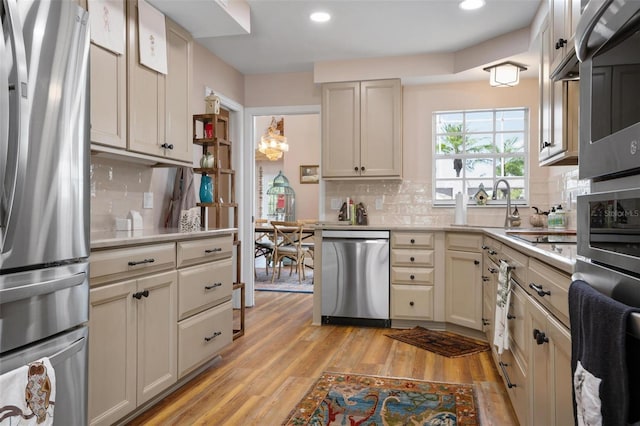 kitchen featuring tasteful backsplash, sink, light hardwood / wood-style flooring, stainless steel appliances, and cream cabinets