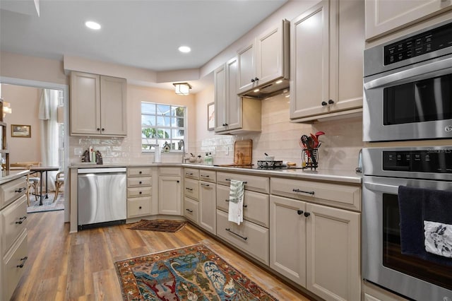 kitchen with stainless steel appliances, tasteful backsplash, and light hardwood / wood-style flooring