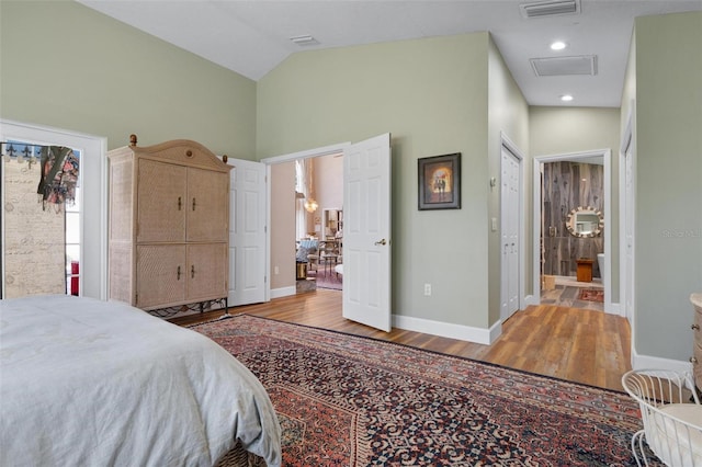 bedroom featuring light hardwood / wood-style floors, high vaulted ceiling, ensuite bathroom, and a closet