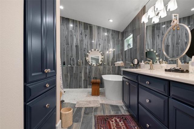 bathroom with tile walls, lofted ceiling, a tub, and vanity