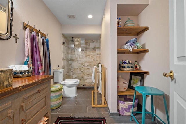 bathroom featuring a tile shower, vanity, toilet, and tile patterned floors