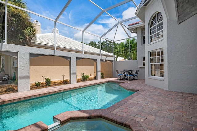 view of swimming pool with glass enclosure, an in ground hot tub, and a patio area