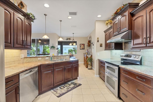 kitchen featuring light stone counters, light tile patterned flooring, sink, decorative light fixtures, and appliances with stainless steel finishes