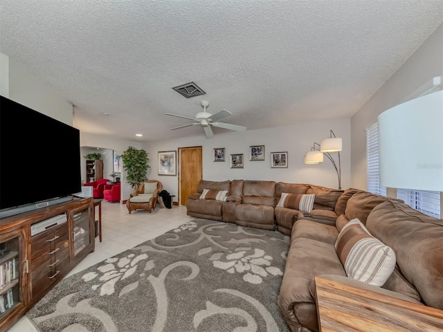 living room with ceiling fan, a textured ceiling, and light tile patterned floors