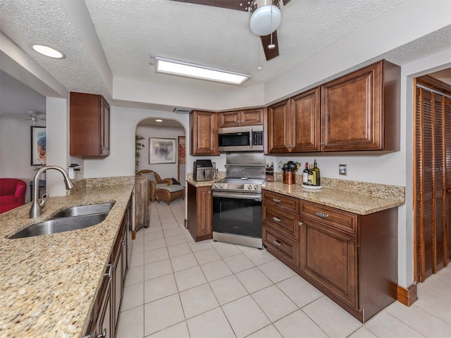 kitchen featuring sink, light stone countertops, stainless steel appliances, and a textured ceiling