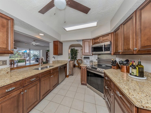 kitchen with light stone countertops, stainless steel appliances, a textured ceiling, and sink