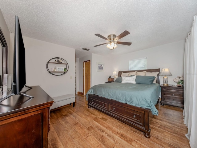 bedroom featuring a textured ceiling, light wood-type flooring, and ceiling fan