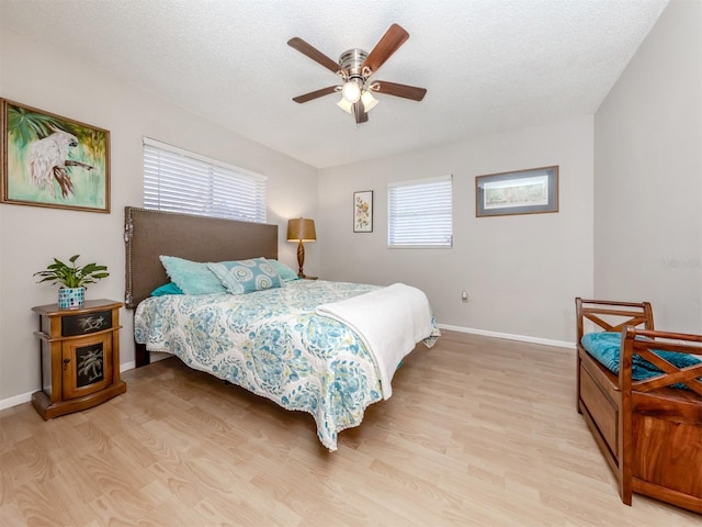 bedroom with ceiling fan, a textured ceiling, and light hardwood / wood-style flooring