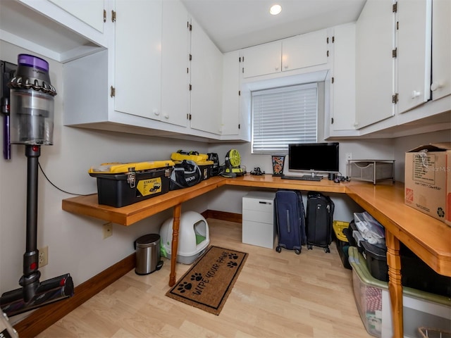 kitchen with white cabinets, built in desk, and light wood-type flooring