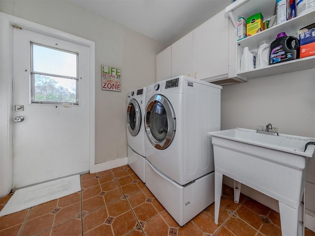 laundry area with dark tile patterned floors, washing machine and dryer, and cabinets