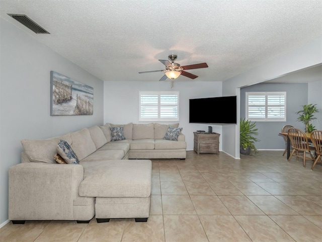 tiled living room featuring ceiling fan, a textured ceiling, and plenty of natural light