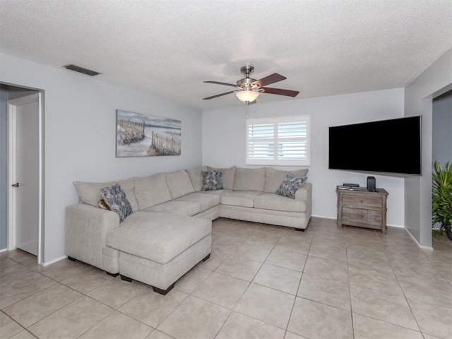 living room with a textured ceiling, light tile patterned flooring, and ceiling fan