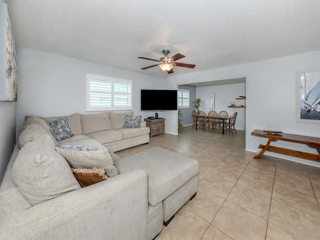 living room featuring a textured ceiling, light tile patterned floors, and ceiling fan