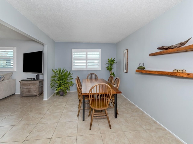 tiled dining space with a textured ceiling and plenty of natural light