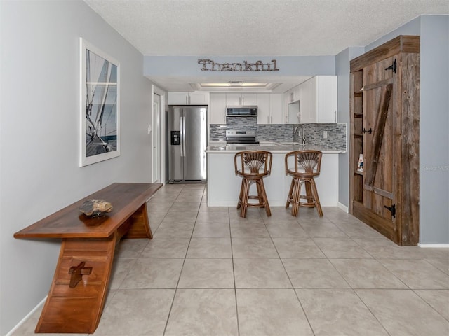 kitchen with decorative backsplash, white cabinets, kitchen peninsula, and appliances with stainless steel finishes